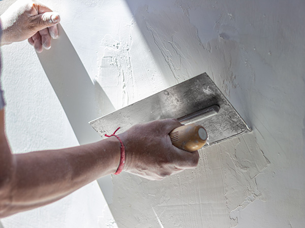 Tradesman plastering a wall with a trowel